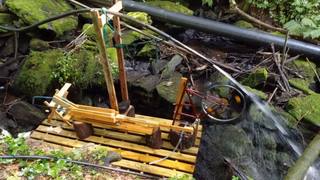 The finished water-powered saw beside a stream